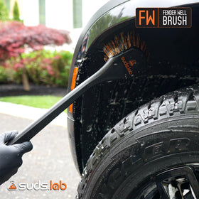 suds.lab brush held by user demonstrating long-handle reach and control