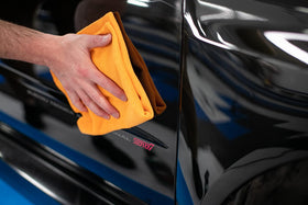 The Rag Company towel used on car paint demonstrating safe coating removal