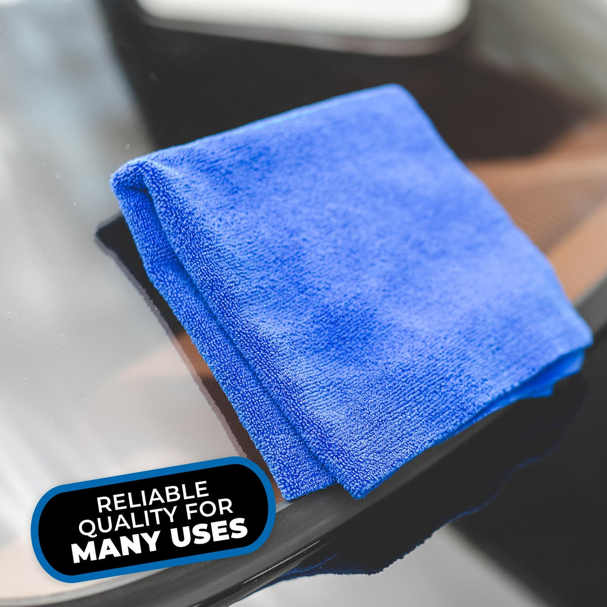 The Rag Company towel next to a hand to show 16x16 size and handling comfort