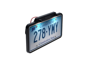 Thule license plate holder beside a standard license plate showing scale and low-profile benefit