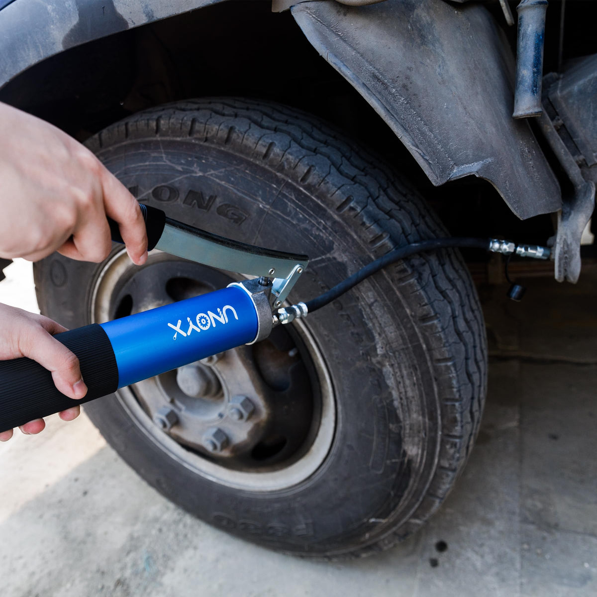 UNOYX grease gun next to hand for scale showing lightweight benefit