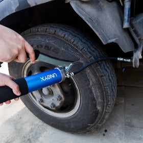 UNOYX grease gun next to hand for scale showing lightweight benefit