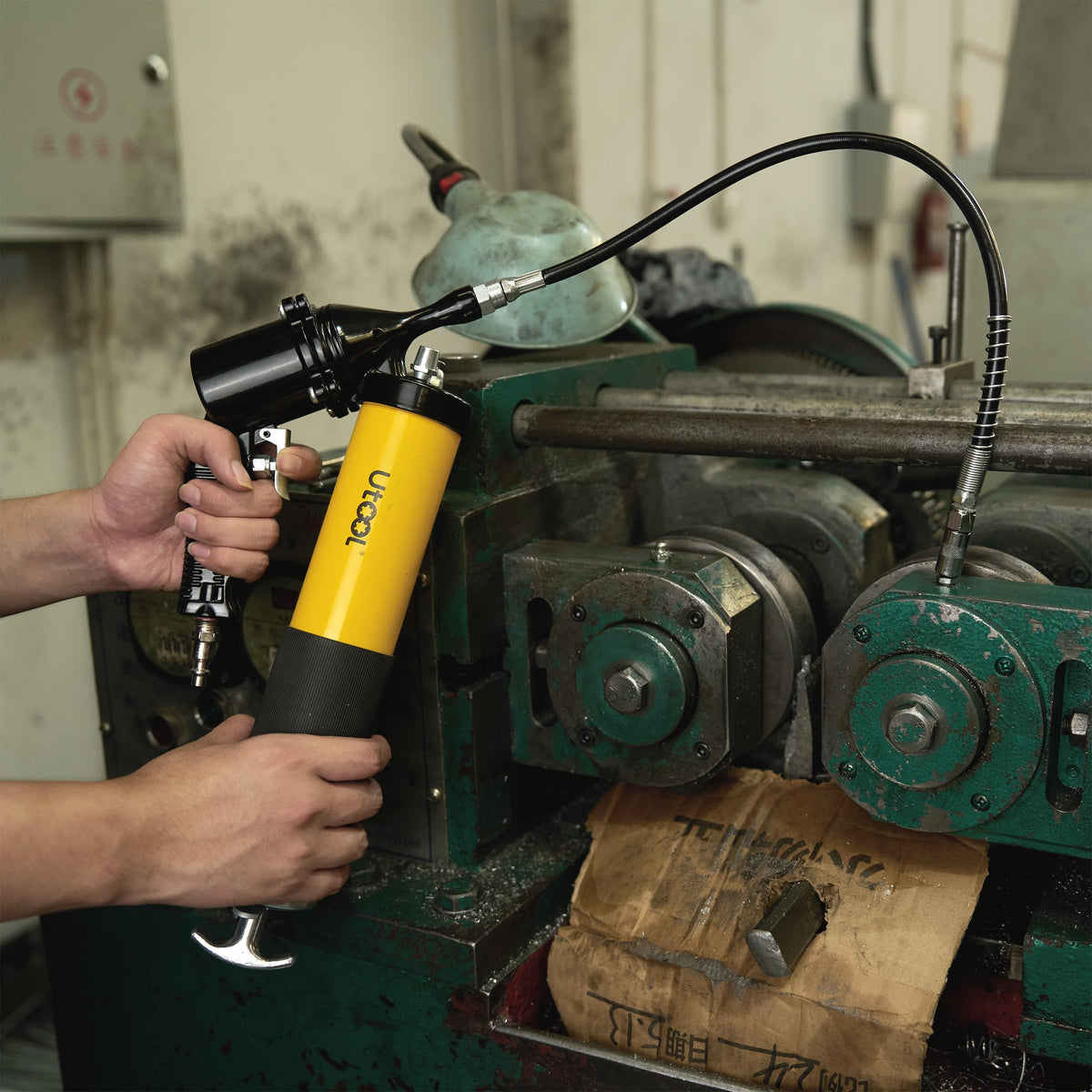 UTOOL grease gun in use on tractor grease fitting, enabling efficient continuous lubrication